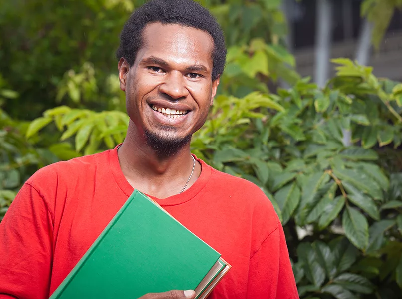 Portrait of a happy smiling young male student from south east asia carrying school books