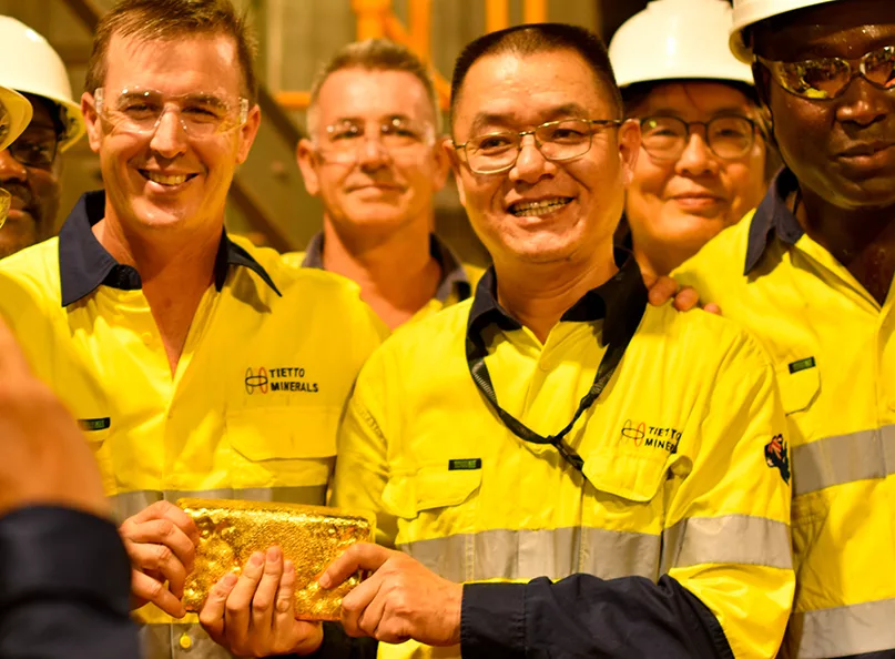 Tietto Minerals Caigen Wang pictured centre, holding a gold bar with colleagues