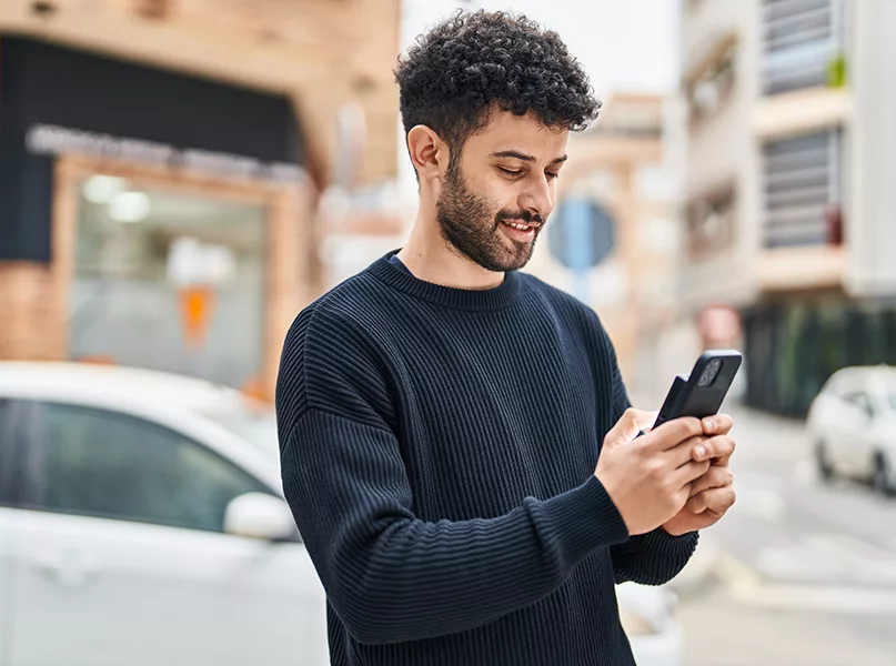 Young man smiling confident using smartphone at street