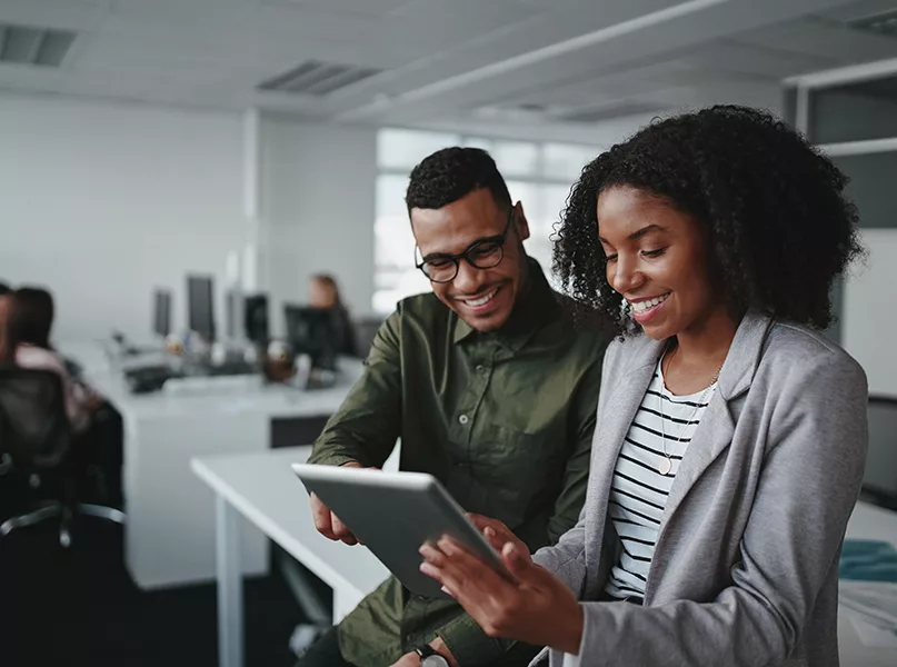 Smiling professionals working online with a digital tablet in office