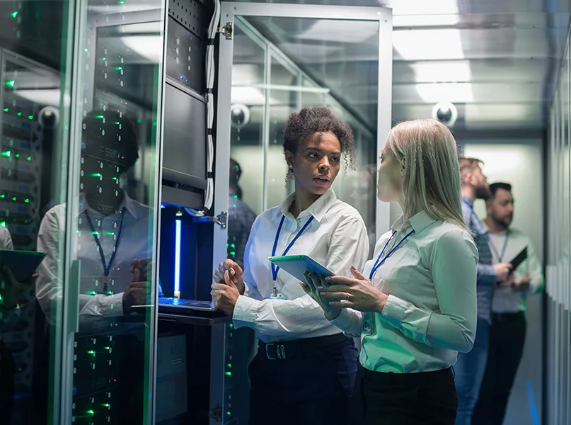 Two women working in a data center with rows of server racks