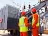 electricians standing next to a transformer