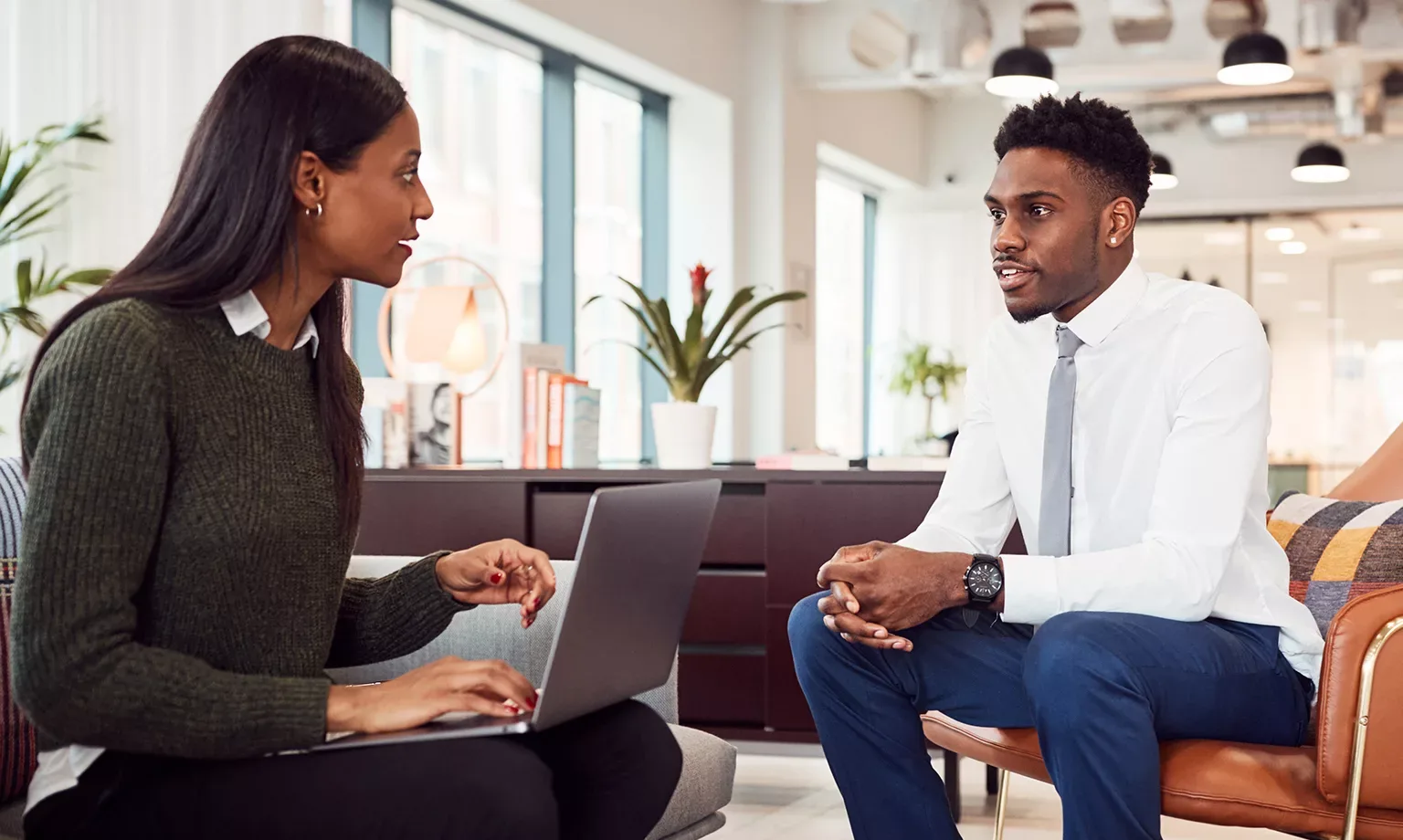Businesswoman Interviewing Male Job Candidate In Seating Area Of Modern Office