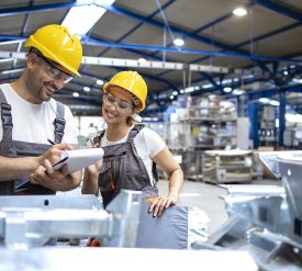 Factory workers checking quality of products in large industrial hall.