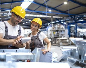 Factory workers checking quality of products in large industrial hall.