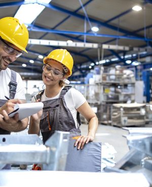 Factory workers checking quality of products in large industrial hall.