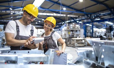 Factory workers checking quality of products in large industrial hall.