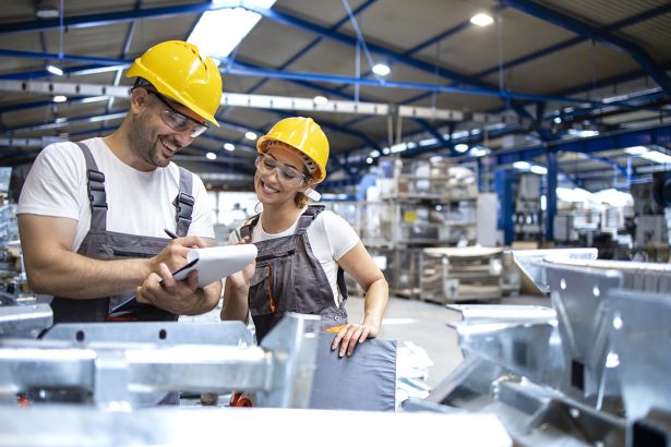 Factory workers checking quality of products in large industrial hall.