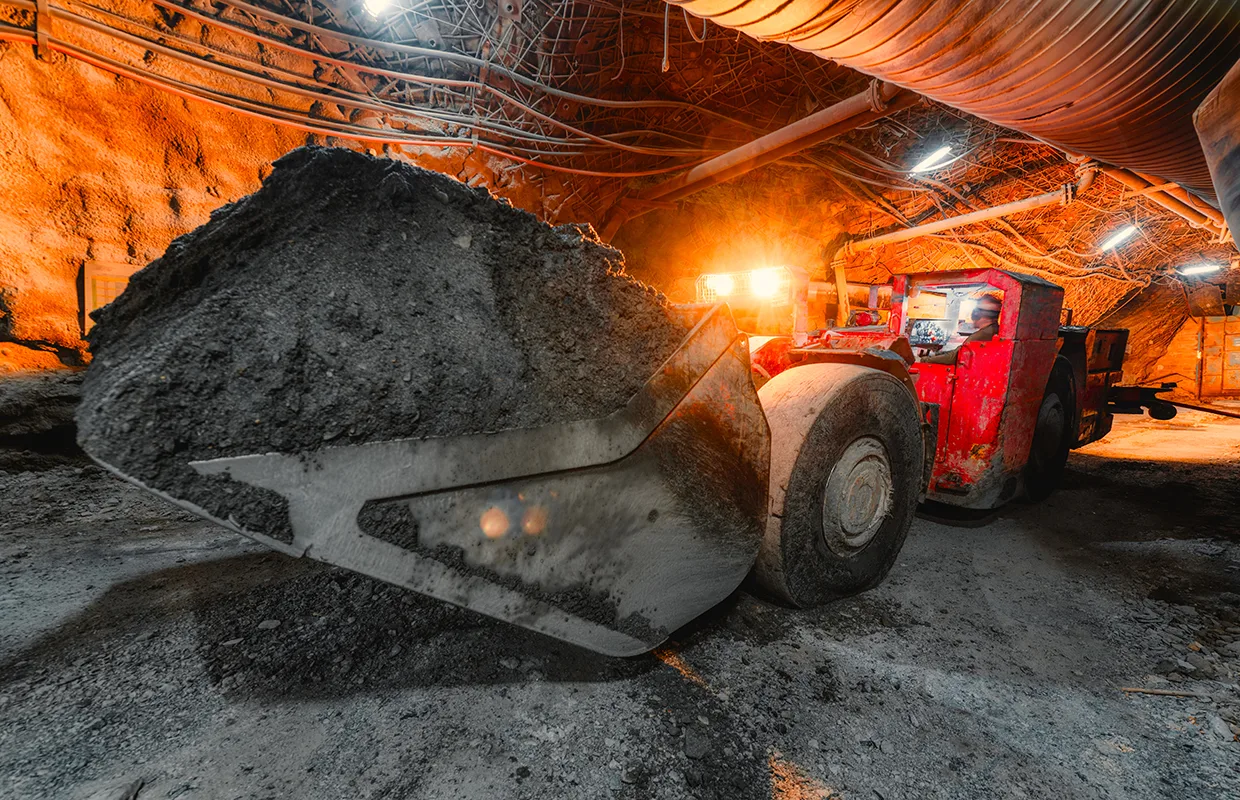 An underground loading machine carries a full bucket of ore. © istock/ukwazi