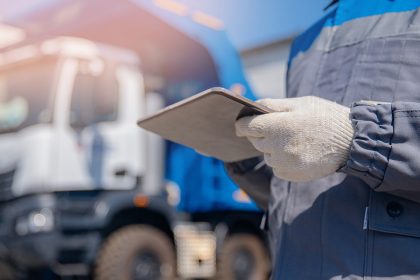 Dump truck driver man in uniform with tablet computer controls loading of cargo or coal